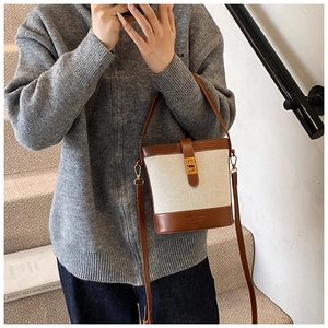 Vue détaillée du sac seau en cuir marron et toile blanche avec un fermoir doré élégant