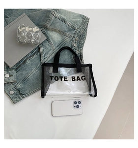 Detail view of the transparent PVC tote bag with black mesh sides and TOTE BAG print
