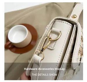 Dettaglio della fibbia in metallo dorato e trama intrecciata di una borsa beige