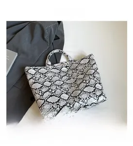 Detail shot of chic snakeskin pattern tote bag paired with a stylish grey blazer