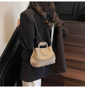 Detail of taupe litchi texture bucket bag with metal handle and decorative gold chain