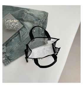 Detail of transparent PVC tote bag with black canvas trim and TOTE letter print