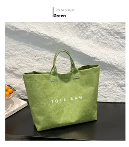 Detail view of the green tote bag showing textured fabric and bold white lettering