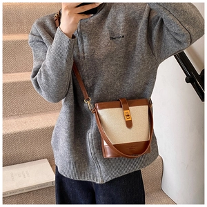 Détail du sac seau en toile beige et cuir marron avec bandoulière et logo gravé