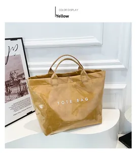 Detail view of the yellow waterproof tote bag with sturdy handles and bold white text