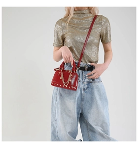 Detailansicht rote glänzende Mini-Muscheltasche mit Goldnieten und Kette an einem Modell