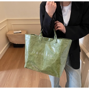 Détail du sac cabas vert en tissu texturé avec couche PVC et texte blanc