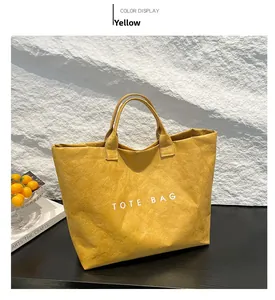 Detailed view of yellow TOTE BAG showing crinkled DuPont paper texture on a black table