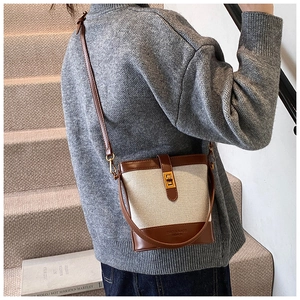 Détail du sac seau en toile avec bordure en cuir et fermoir rotatif doré élégant