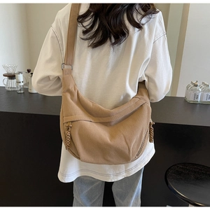 Back view of a khaki corduroy crossbody bag with wide strap on a model in a cafe
