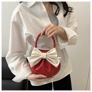 Dettaglio della borsa rossa e bianca con fiocco e manico ad anello in stile chic