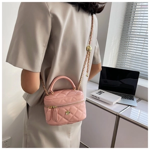 Detail of pink quilted mini box bag with golden floral clasp and metal chain strap
