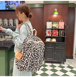 Fashion leopard print backpack with toast plush charm shown in a cozy cafe setting