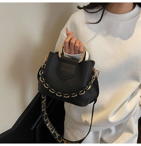Close-up of black lychee grain leather bag with a unique gold metal semicircular handle