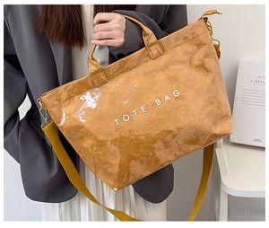 Close-up of brown Tyvek tote bag with white TOTE BAG text and yellow shoulder strap