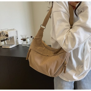 Detail of light brown corduroy crescent bag with textured fabric and braided knot detail