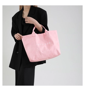 Pink printed tote bag in textured tyvek material held by a model in a black suit