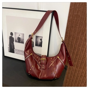 Détail du sac demi-lune bordeaux avec rivets dorés, glands et bandoulière ajustable