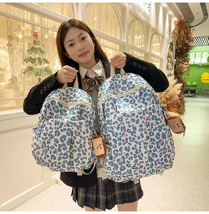Detailed comparison of blue leopard print backpacks with cute cartoon biscuit charm decor