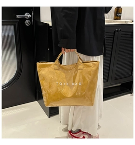Detail view of mustard yellow waterproof tote bag with white TOTE BAG text print