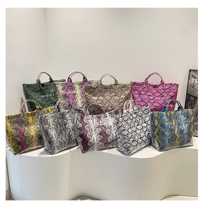 Collection of snake print tote bags in nine colors displayed on a white stand