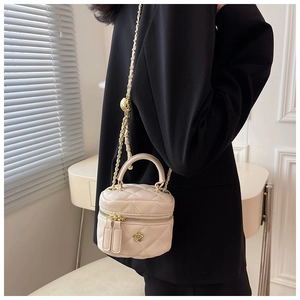 Detail view of quilted leather box bag with golden chain and camellia logo on model