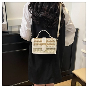 Dettaglio di una borsa a tracolla intrecciata beige con fibbia in metallo su una modella
