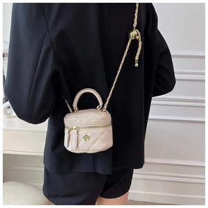 Detail of light pink quilted mini vanity bag with golden camellia logo and chain strap