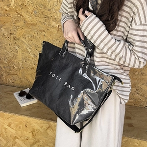 Detail of glossy pleated tote bag with white TOTE BAG text and wide shoulder strap