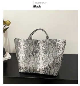Detail of grey-black python pattern tote bag with white TOTE BAG text and dual handles