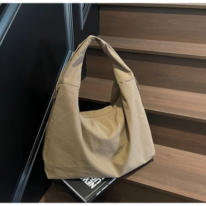 Bolso hobo grande caqui con cordón ajustable sobre una escalera de madera