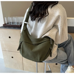 Detail of dark green corduroy hobo bag featuring woven zipper pull and crossbody strap