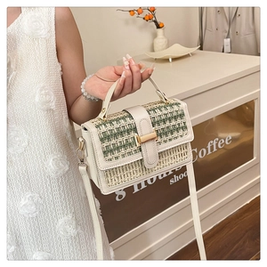 Dettaglio di borsa in paglia intrecciata con finiture in pelle crema e fibbia dorata