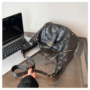 Détail d'un sac en cuir noir avec rivets dorés, fermetures éclair et franges punk chic