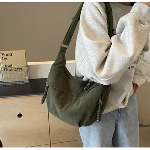 Detail of dark green corduroy crossbody bag with adjustable strap and knotted zipper puller