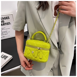 Detail of neon yellow quilted mini box bag with chain strap worn over green blazer