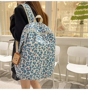 Detail view of canvas backpack featuring blue and pink leopard print and plush bread charm