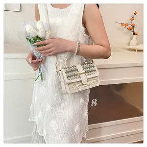Borsa a tracolla in paglia a righe beige e verdi indossata da modella in pizzo
