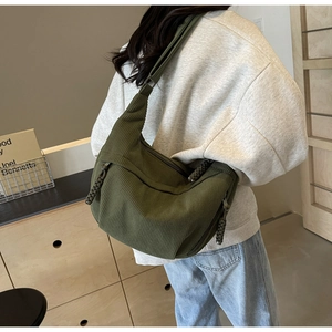 Detail of dark green corduroy hobo bag showing large capacity and textured fabric on model