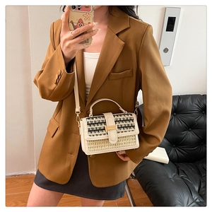 Dettaglio della borsa a tracolla in paglia intrecciata con fibbia dorata e finiture in beige
