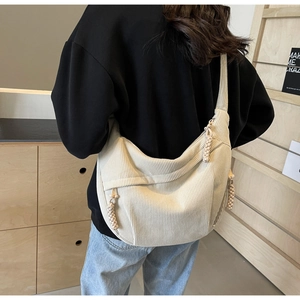 Detail of off-white corduroy crossbody bag featuring half-moon design and woven zipper pull