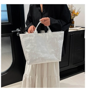 Close-up of white Dupont paper tote bag with wrinkled texture and embossed TOTE BAG lettering