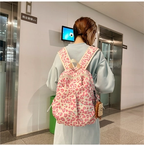 Detail of pink leopard print backpack with multiple pockets and cute bear charm accessory