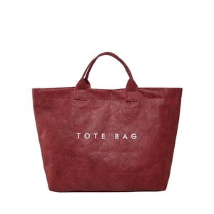 Minimalist deep red tote bag with crinkle texture and white lettering on white background