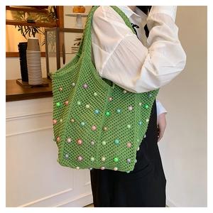 Detail of green handmade woven tote bag with colorful pearls and hollow knit texture
