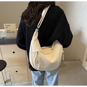 Detail of off-white corduroy hobo bag showing woven rope zipper and crescent shape