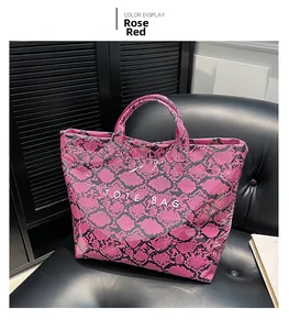 Detail of rose red snake-skin pattern tote bag with dual handles on a black leather seat