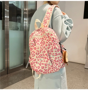 Detail view of pink leopard print backpack with a cute brown teddy bear charm accessory