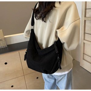 Close-up of black corduroy hobo bag on shoulder showing texture and crescent shape
