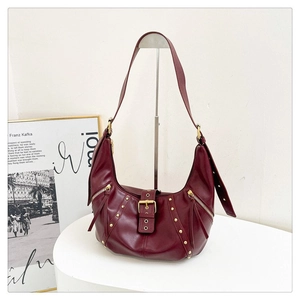 Détail du sac hobo en cuir bordeaux avec rivets dorés et accents de double fermeture